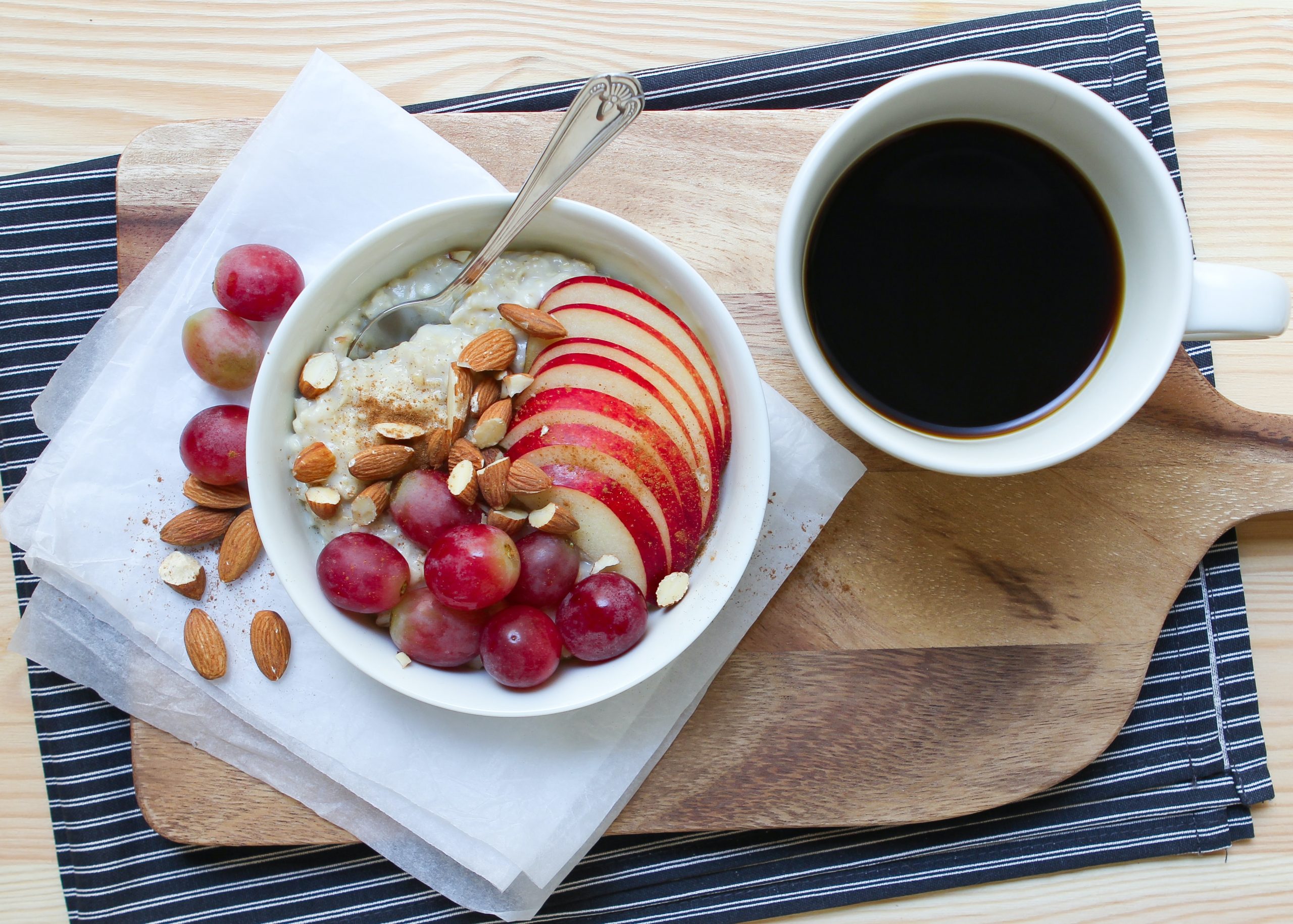 A portion of porridge with apples and a black coffee.